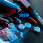 Assorted illegal drugs and paraphernalia on dark surface
