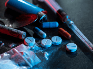 Assorted illegal drugs and paraphernalia on dark surface