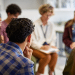 Group counseling session with several people sitting in a circle, one person taking notes. Image represents Summit County mandatory DV counseling and Colorado domestic violence treatment programs required for offenders.