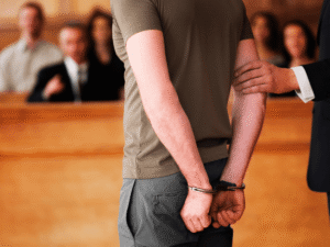 Handcuffed defendant standing in a courtroom next to a lawyer, symbolizing the critical initial steps of securing bail pretrial motions Colorado.